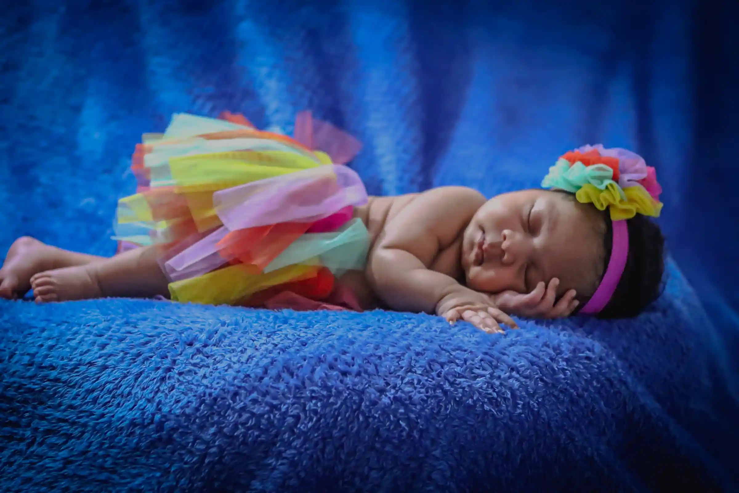 Un bebé de 3 meses duerme serenamente sobre su mano, envuelto en un pequeño traje de hada para un retrato infantil tranquilo